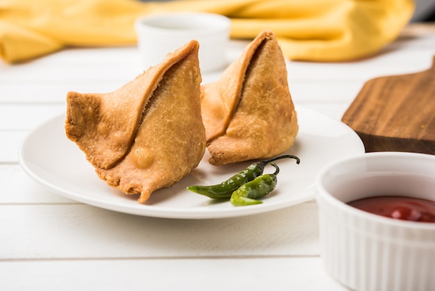 Veg Samosa, lanche da Índia para a hora do chá servido com pimenta verde frita. Foco seletivo