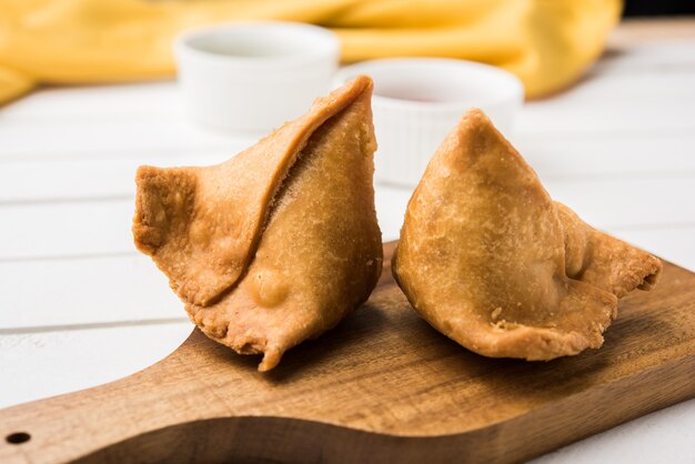 Veg Samosa, Tee-Snack aus Indien, serviert mit grün gebratenen Chilis. Selektiver Fokus