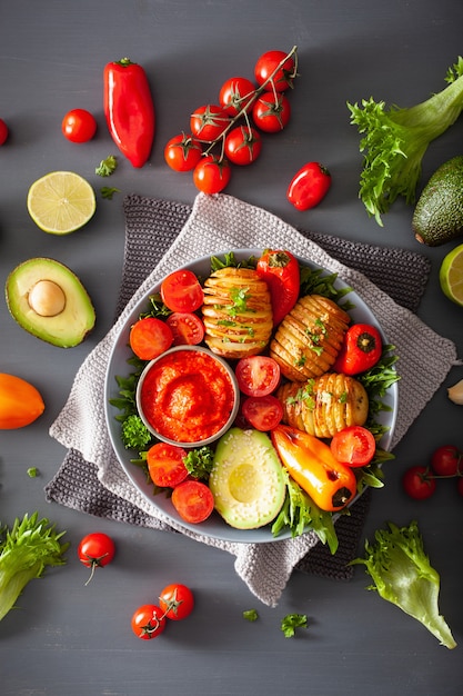 Vegan Buda Bowl. almuerzo saludable con papas hasselback, aguacate, tomate, pimientos y salsa de pimientos