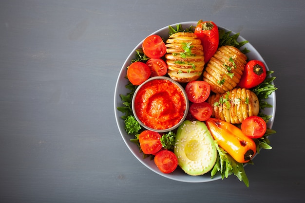 Vegan Buda Bowl. almuerzo saludable con papas hasselback, aguacate, tomate, pimientos y salsa de pimientos