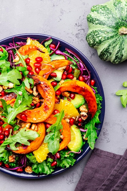 Vegan saudável comendo salada de abóbora de outono com mel assado fatias de abóbora alface rúcula sementes de romã e nozes Comida de conforto Vista superior