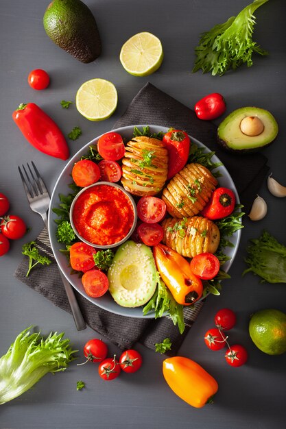 Vegane Buddha-Schale. gesunde Schüssel mit Hasselback-Kartoffel, Avocado, Tomate, Paprika und Pfeffersauce