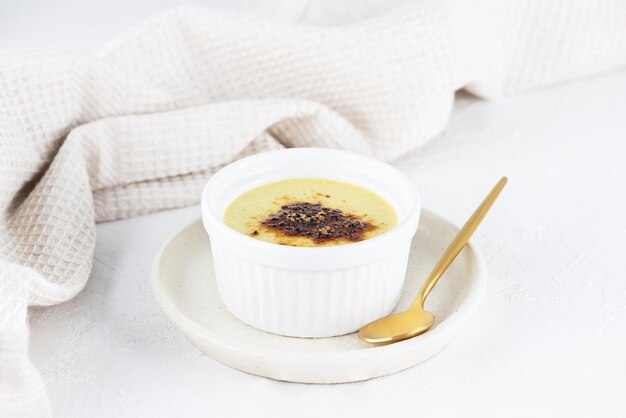 Vegane Crème Brlée in einer weißen Schüssel auf dem Tisch. Zucker-, gluten- und laktosefrei.