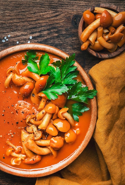 Vegane cremige Kürbissuppe mit Champignons, Paprika und Petersilie Gesundes vegetarisches Slow Food im Winter oder Herbst Holzschale auf Holztisch Hintergrund Ansicht von oben