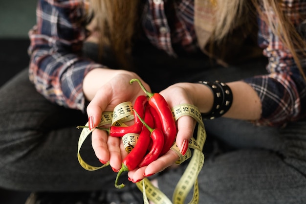 Vegane Ernährung gesunde Ernährungsgewohnheiten natürliche Bio-Produkte und ausgewogene Ernährung Frau mit frischen Chilischoten mit verdrehtem Maßband in der Hand