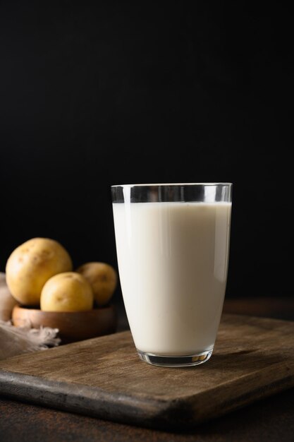 Vegane Kartoffelmilch und Kartoffel auf braunem Hintergrund. Nahansicht. Milchaustauscher auf pflanzlicher Basis und laktosefrei.