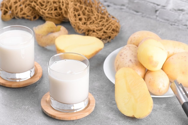 Vegane Kartoffelmilch und Kartoffel auf grauem Steintisch Hintergrund Pflanzlicher alternativer Milchersatz und laktosefrei