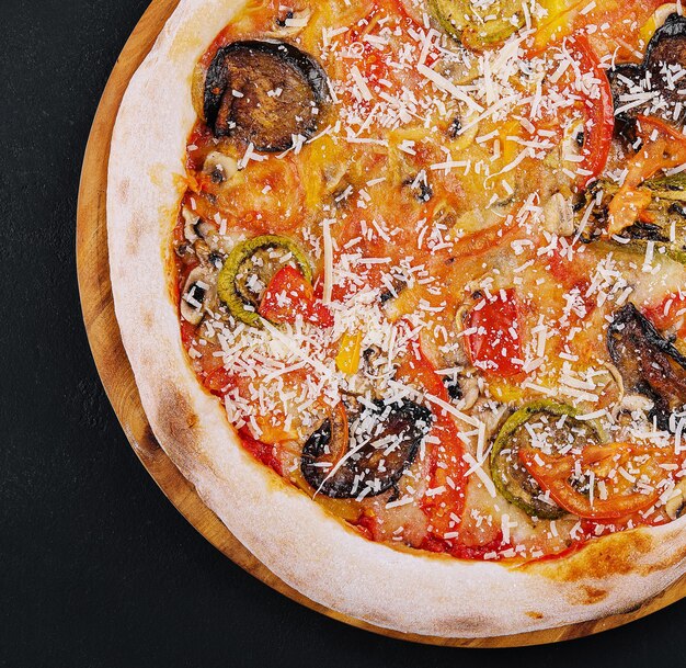 Vegane Pizza mit geröstetem Gemüse auf Holzbrett