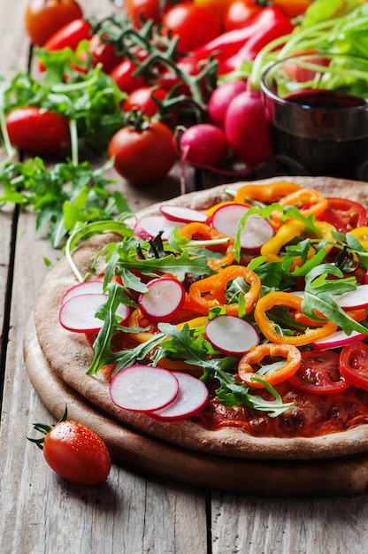 Foto vegane pizza mit radieschen, tomate und paprika