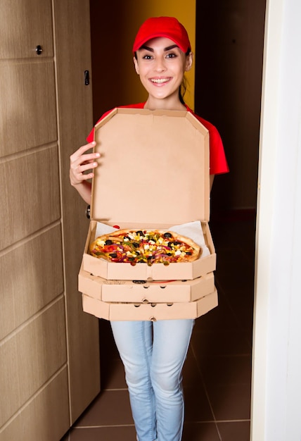 Vegane Pizzalieferung Kurierin in roter Uniform