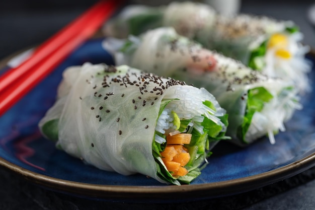 Vegane Reispapierrollen mit Gemüse und Sesam, serviert auf einem Teller, essfertig