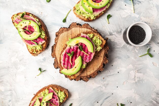 Vegane Sandwiches mit Avocado-Wassermelonen-Rettich Leckeres Frühstück oder Snack auf hellem Hintergrund, Draufsicht