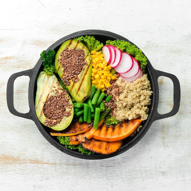 Vegane Schüssel: Quinoa, Avocado, Kürbis mit Bohnen und Mais in einer schwarzen Schüssel. Diät. Ansicht von oben. Freier Platz für Text.