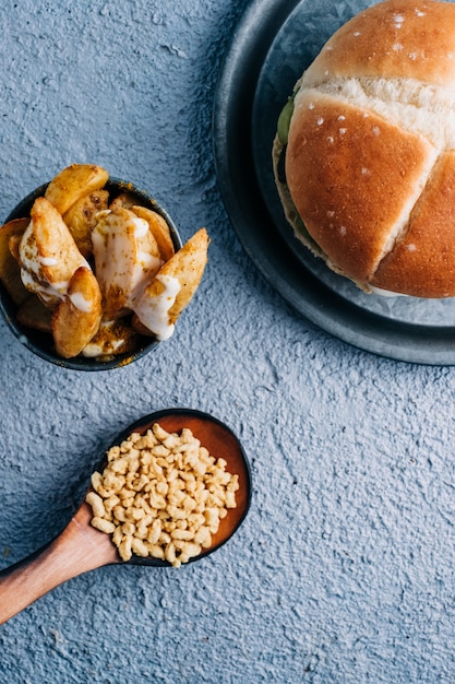 Veganer Burger mit Pommes Frites mit Gewürzen und Soße in einer Metallschale auf blauem Tischhintergrund