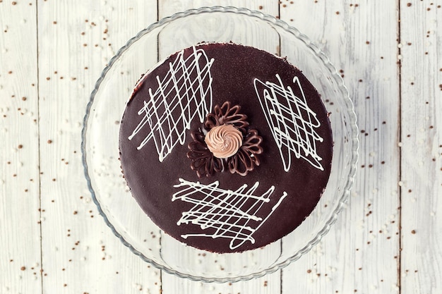 Veganer Kuchen aus dunkler Schokolade mit Sahne auf Holzhintergrund