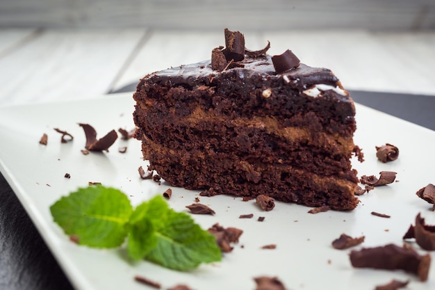 Veganer Kuchen aus dunkler Schokolade mit Süßigkeiten auf Holzhintergrund