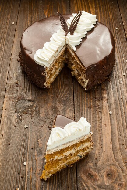 Veganer Kuchen aus dunkler Schokolade mit Süßigkeiten und Nüssen auf Holzhintergrund