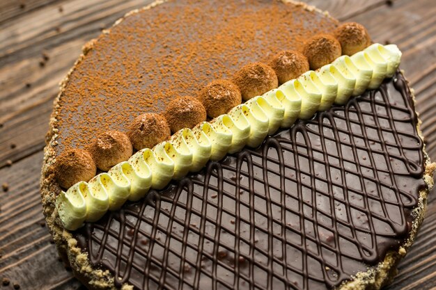 Foto veganer kuchen aus dunkler schokolade mit süßigkeiten und nüssen auf holzhintergrund