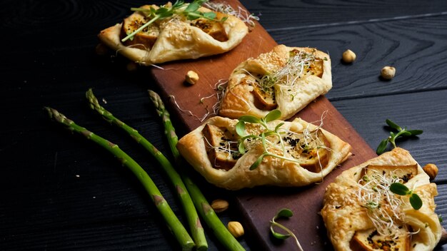 Veganer Lebensmittel-Blätterteig-Umschlag mit geräuchertem Käse, schwarzer Holzhintergrund, Essen flach