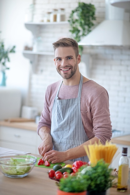 Veganer Lebensstil. Ein junger Mann, der Gemüse für einen Salat hackt