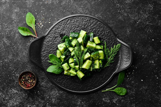 Veganer Salat mit Gurke und Dill auf einem schwarzen Teller Rustikaler Stil Draufsicht Freier Platz für Ihren Text