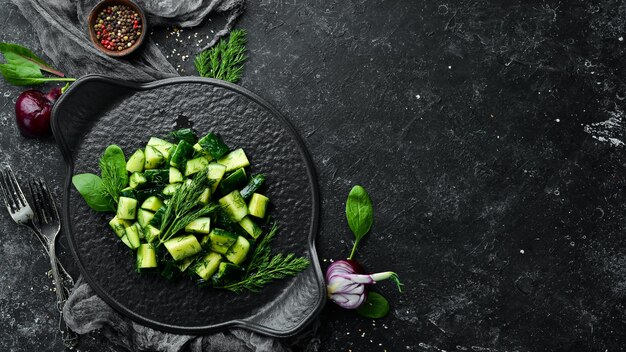 Veganer Salat mit Gurke und Dill auf einem schwarzen Teller Rustikaler Stil Draufsicht Freier Platz für Ihren Text