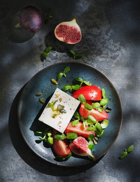 Veganer Sommersalat mit Fetakäse, frischen Feigen, Tomaten, Feigen und grünen Blättern. Gesunder Salat.