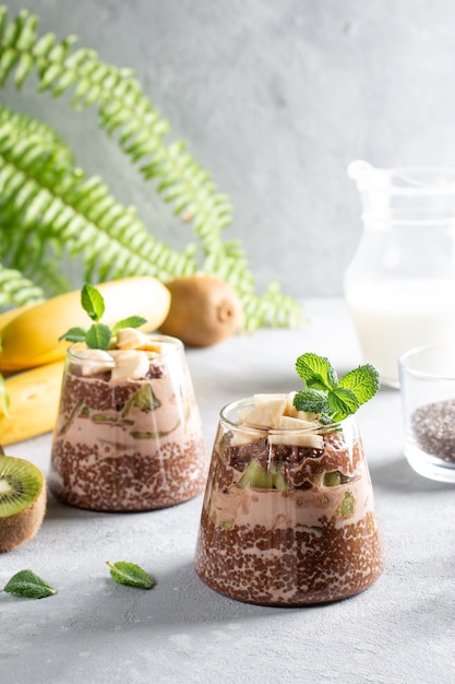 Veganes Dessert, Chia-Pudding mit Kiwi und Banane auf grauem Tisch. Superfood