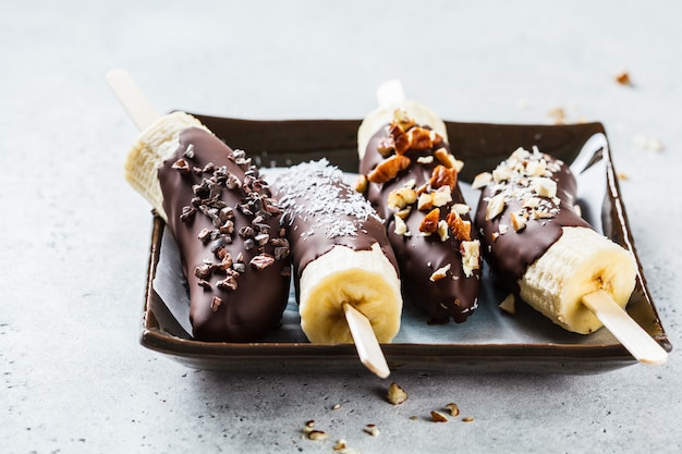 Veganes Dessert für Kinder. Banane in dunkler Schokolade mit Nüssen.