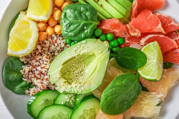 Veganes Lebensmittelkonzept: Quinoa mit Avocado, Gurken, grünen Erbsen, Kichererbsen, Spinat und Zitrusfrüchten. Ansicht von oben.