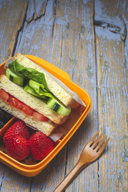 Veganes Sandwich im Plastikbehälter auf hölzernem Hintergrund