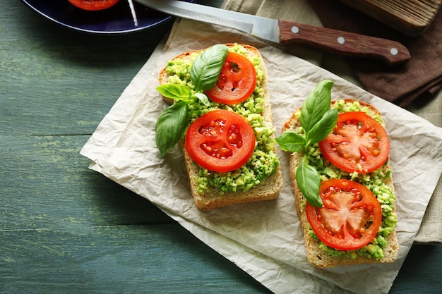 Veganes Sandwich mit Avocado und Gemüse auf Schneidebrett auf Holzhintergrund