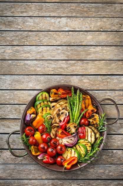 Veganes, vegetarisches, saisonales, sommerliches Essenskonzept. Gegrilltes Gemüse in einer Pfanne auf einem Holztisch. Draufsicht flach kopieren Raumhintergrund