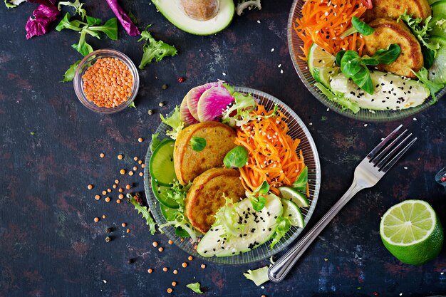 Vegano Buda tazón cena mesa de comida. Comida sana. Tazón de almuerzo vegano saludable. Buñuelo con lentejas y rábano, aguacate, ensalada de zanahoria. Endecha plana. Vista superior