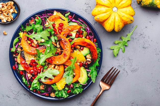 Foto vegano saludable comer ensalada de calabaza de otoño con rodajas de calabaza de miel al horno lechuga rúcula semillas de granada y nueces comida reconfortante vista superior