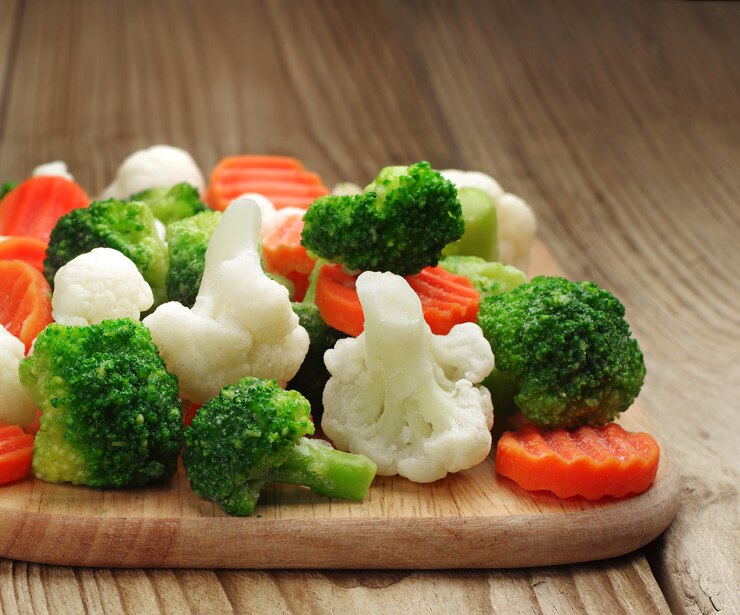 Vegetais diferentes congelados em uma tábua de cortar