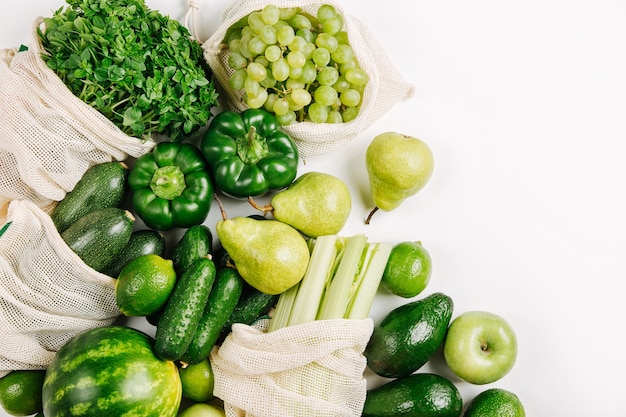 Vegetais orgânicos e verduras frescas em sacos de produtos reutilizáveis em fundo branco