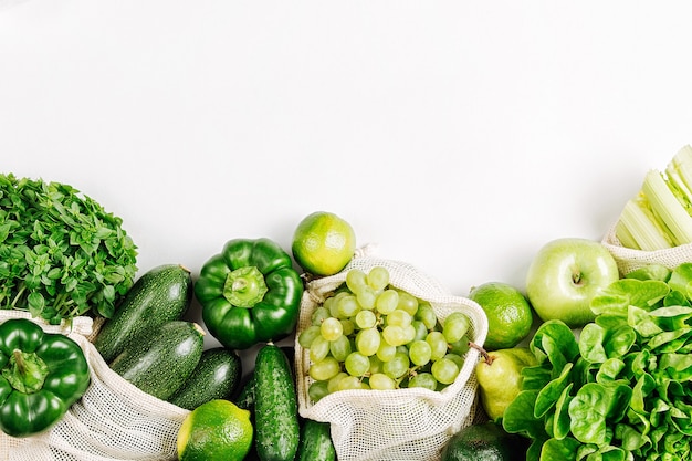 Vegetais orgânicos e verduras frescas em sacos de produtos reutilizáveis em fundo branco