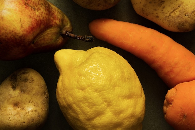 Vegetais orgânicos feios e frutas - cenoura, batata, limão, pêra. Produção deformada, conceito de desperdício de alimentos imperfeito deformado. Vista do topo.