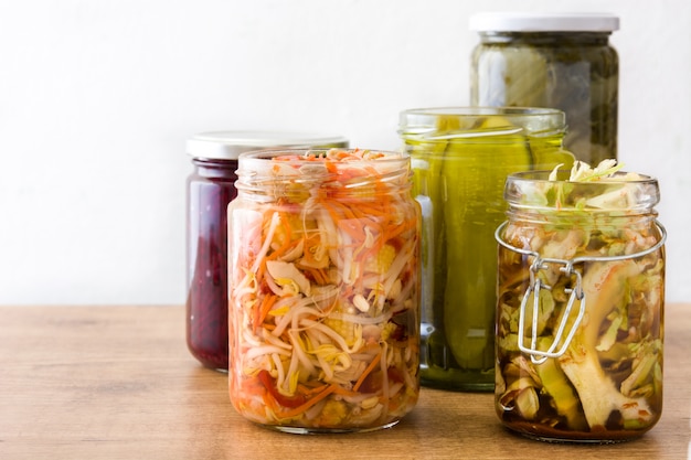 Foto vegetais preservados fermentados em pote na mesa de madeira.