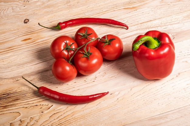 Vegetais suculentos, pimentão e pimenta e tomate em uma mesa de madeira.