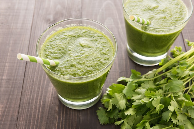 Vegetais verdes saudáveis e smoothie da fruta verde na mesa de madeira rústica