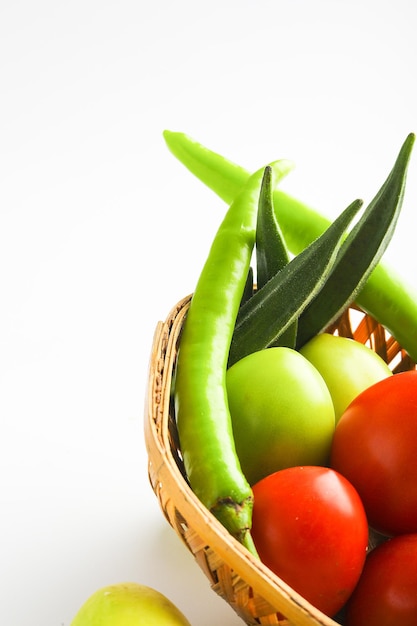 Vegetales crudos en cuenco de madera sobre fondo blanco.