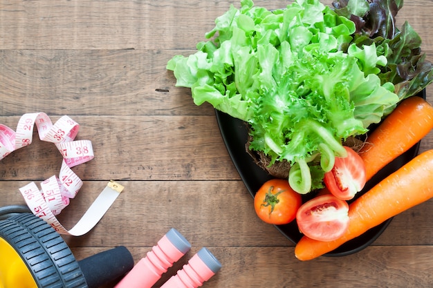 Foto vegetales y equipos de fitness sobre fondo de madera.