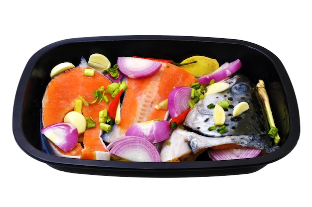 Vegetales y salmón en bandeja contra un fondo blanco