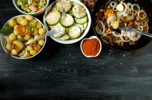 Vegetales . Salsa de calabacín frita en un plato. Patatas hervidas jóvenes con eneldo en un tazón. Rebozuelos fritos con cebolla dorada en una sartén. copyspace