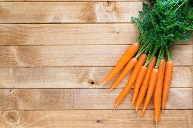 Vegetales de zanahoria fresca con hojas en el fondo de madera.