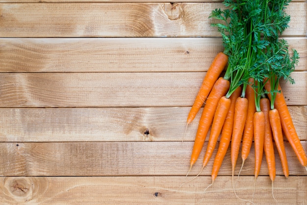 Vegetales de zanahoria fresca con hojas en el fondo de madera.