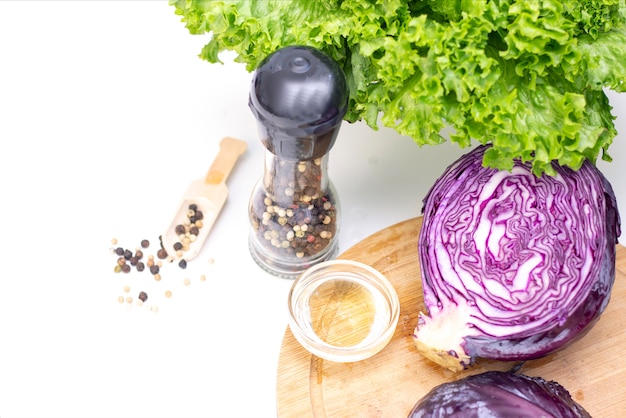 Vegetarianismo. ingredientes para una ensalada ligera. Repollo morado, lechuga, guisantes y aceite de oliva sobre una mesa blanca.