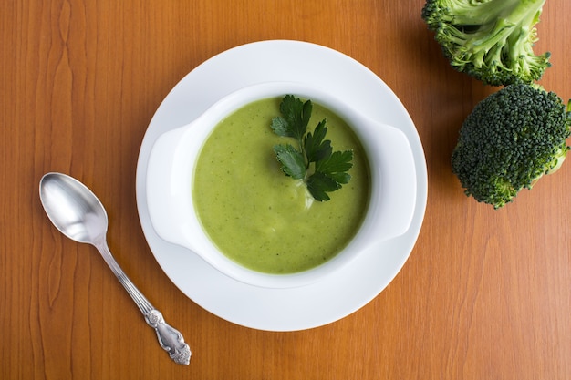 Vegetarische Brokkoli-Püree-Suppe in der weißen Schüssel auf dem hellbraunen hölzernen Hintergrund.